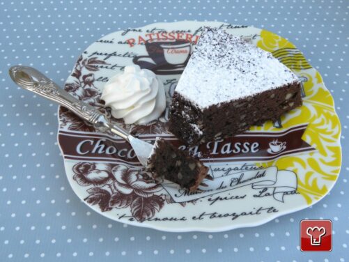 Una fetta di torta Caprese vista da vicino: mollica compatta e umida con le mandorle a pezzi