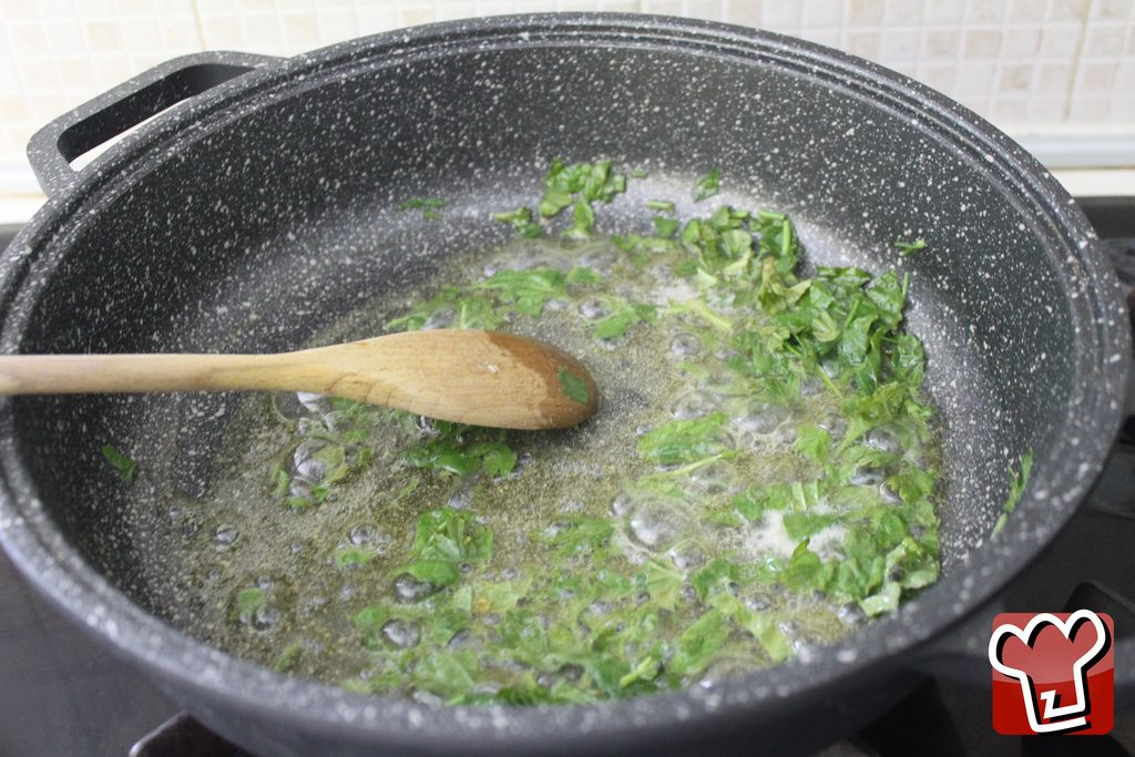 Prezzemolo e basilico tritati che sfrigolano nell'olio e nel burro, prima che entri il pollo