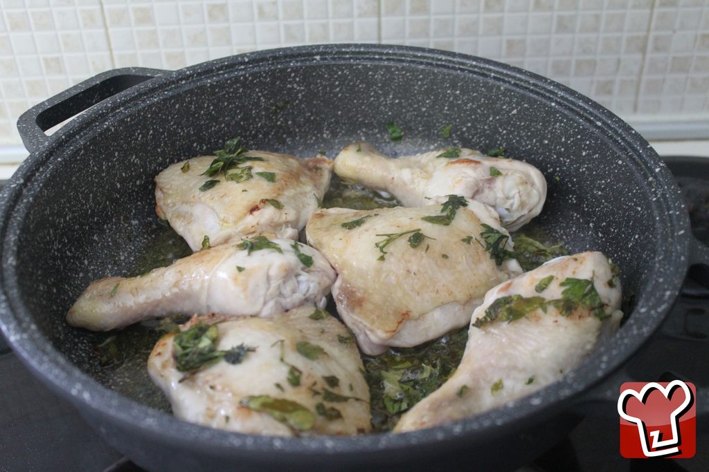 I pezzi di pollo rosolati nella padella, dorati e con le erbe attaccate alla pelle