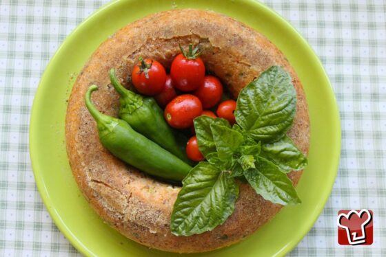 Il sartù di riso sformato intero sul piatto, dorato, con il buco centrale guarnito